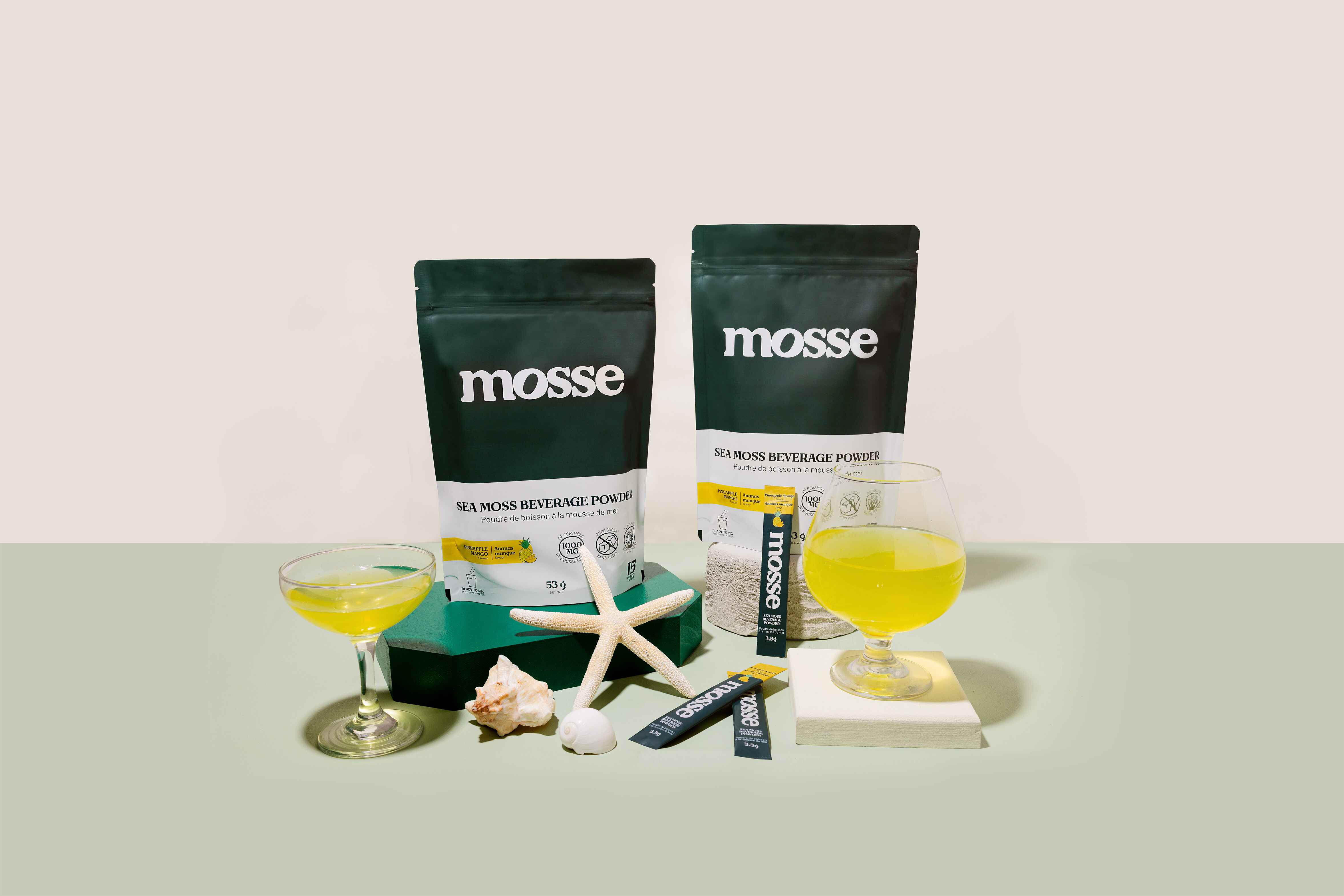 product image of two pouches of sea moss beverage powder with shells, and beverage filled glasses